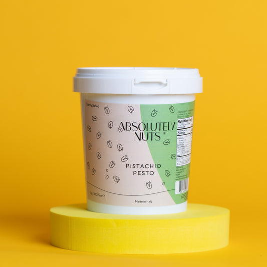 Container of 'Absolutely Nuts' Pistachio Pesto on a yellow background