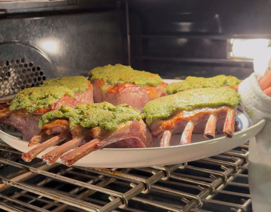 Lamb chops with green pistachio herb sauce being placed into an oven.